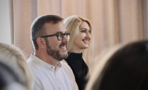 Чоловік в окулярах та жінка зі світлим волоссям сидять у приміщенні.