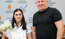 Жінка та чоловік позують для фото з грамотою та квітами.