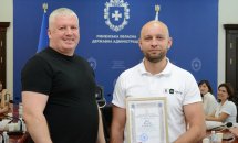 Двоє чоловіків позують для фото, один з них тримає грамоту у руках.