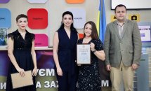 Троє жінок в темному одязі та чоловік позують для фото, дві жінки тримають грамоти.