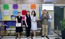 Троє жінок та чоловік позують для фото, дві жінки тримають грамоти.