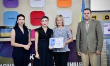 Три жінки та чоловік позують для фото, одна жінка тримає подяку.