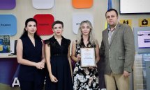Три жінки та чоловік позують для фото, одна жінка тримає грамоту.