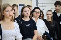 Група людей перебуває у приміщенні, позаду інформаційні стенди.