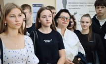 Група людей перебуває у приміщенні, позаду інформаційні стенди.