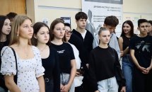 Група молодих людей стоїть у приміщенні, на задньому плані видно інформаційний банер.