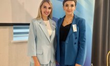 Дві жінки в діловому одязі позують для фото у приміщенні.