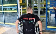 Чоловік на кріслі колісному біля входу у приміщення.