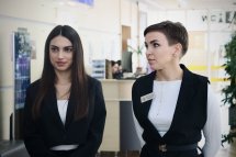 Дві жінки у діловому одязі перебувають у приміщенні.