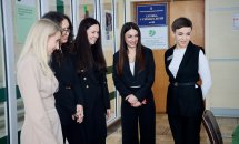П'ять жінок стоять у приміщенні та посміхаються.