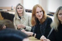 Три жінки сидять у приміщенні та посміхаються