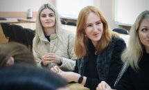 Три жінки сидять у приміщенні та посміхаються