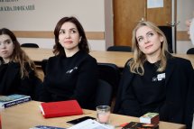 Дві жінки сидять столом та дивляться убік.