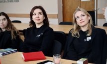Дві жінки сидять столом та дивляться убік.