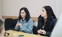 Дві жінки з темним волоссям сидять за столом.