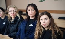 Група жінок сидять за столом та дивляться убік.