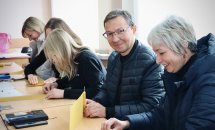 Група людей сидить за столом та роблять свічки.
