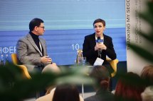 Чоловік та жінка сидять у приміщенні, на задньому фоні - екран