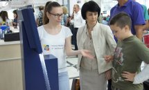 Жінка у білому одязі спілкується з хлопчиком та жінкою біля терміналу.