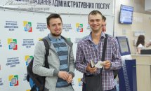 Двоє чоловіків позують на фоні банера.