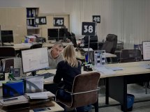 Жінка сидить за робочим місцем і спілкується з чоловіком.