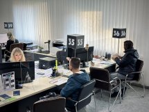 Двоє людей працюють за комп'ютером, а двоє людей сидять навпроти.