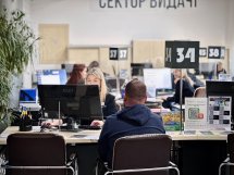 Жінка зі світлим волоссям працює за комп'ютером, чоловік сидить навпроти