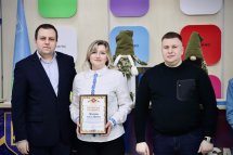 Жінка тримає подяку та стоїть між двома чоловіками.