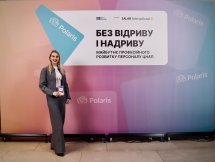 Жінка із світлим волоссям на фоні банера