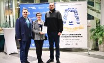 Два чоловіка та жінка стоять на фоні банера.