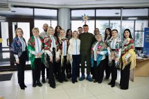 Група людей у вишитих сорочках та чоловік у зеленому одязі.