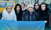 Група жінок перебувають надворі та тримають прапор України у руках.