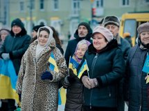 Люди у верхньому одязі тримають прапорці України