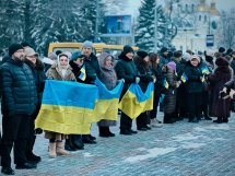 Група людей перебувають на дворі та тримають у руках прапори України