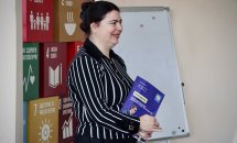 Жінка посміхається та тримає порадник у руках.