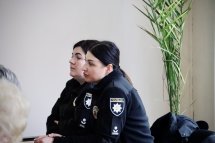 Дві жінки у чорному одязі сидять за столом.