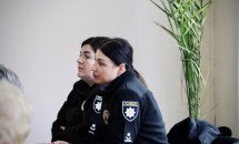 Дві жінки у чорному одязі сидять за столом.