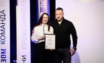 Жінка в білій сорочці тримає подяку, біля неї стоїть чоловік