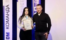 Жінка тримає в руках подяку, чоловік в чорній кофті стоїть біля неї