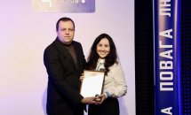 Чоловік в чорному піджаку та жінка в білій сорочці тримають подяку