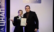 Жінка в діловому одязі тримає подяки в руках, біля неї стоїть чоловік