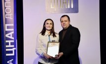 Жінка в білій святковій сорочці та чоловік в чорному піджаку тримають подяку