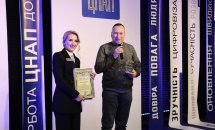 Жінка тримає нагороду, чоловік говорить у мікрофон