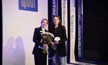 Жінка тримає букет квітів у руках, інша жінка тримає подяку