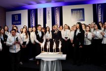 Багато людей перебуває у залі, перед ними торт