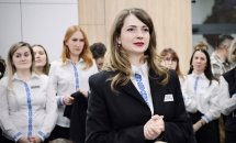 Жінка в чорному піджаку, позаду жінки в білих святкових сорочках