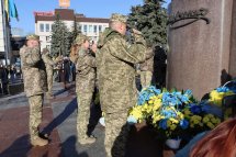 Військові стоять біля пам'ятника з квітами.