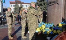 Військові стоять біля пам'ятника з квітами.