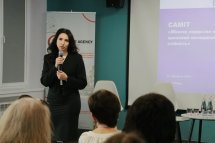 Жінка з темним волоссям тримає мікрофон руках.