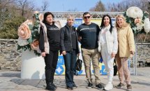 Чотири жінки та чоловік стоять на фоні банера.